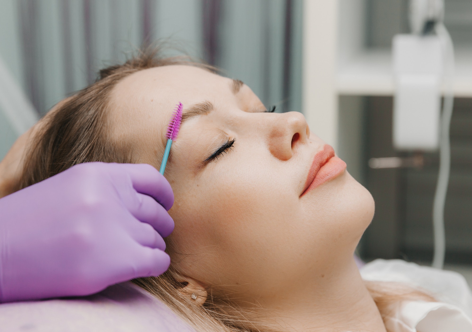 girl makes eyebrow styling in a beauty salon. the master combs his eyebrows. eyelash extensions